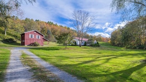 A rural landscape with a red barn and a white house, surrounded by trees and a gravel path. - Bikers' Loft on the Creeper Trail (Damascus)