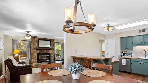 A dining area with a wooden table, woven placemats, and a central vase. - Pet Friendly Relaxing Retreat Walk to DT|King Bed (Cary)