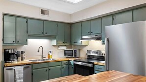 A kitchen with green cabinets, a stainless steel refrigerator, a microwave, a coffee maker, and a sink. - Pet Friendly Relaxing Retreat Walk to DT|King Bed (Cary)