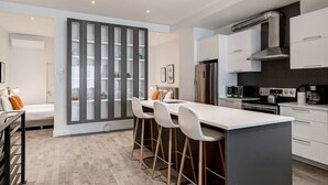 Una cocina moderna con una isla central, taburetes de bar y una zona de comedor con sofá.