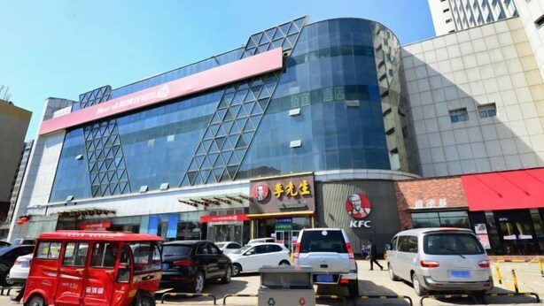 A modern building with a glass facade, a prominent KFC sign, and a red vehicle in the foreground. - Taiyuan Baiyi Boutique Hotel (Taiyuan)