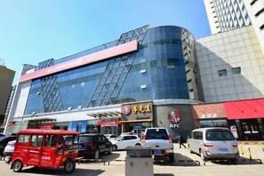 Egy modern épület, üveg homlokzattal, feltűnő KFC felirattal, és egy piros színű járművel az előtérben.