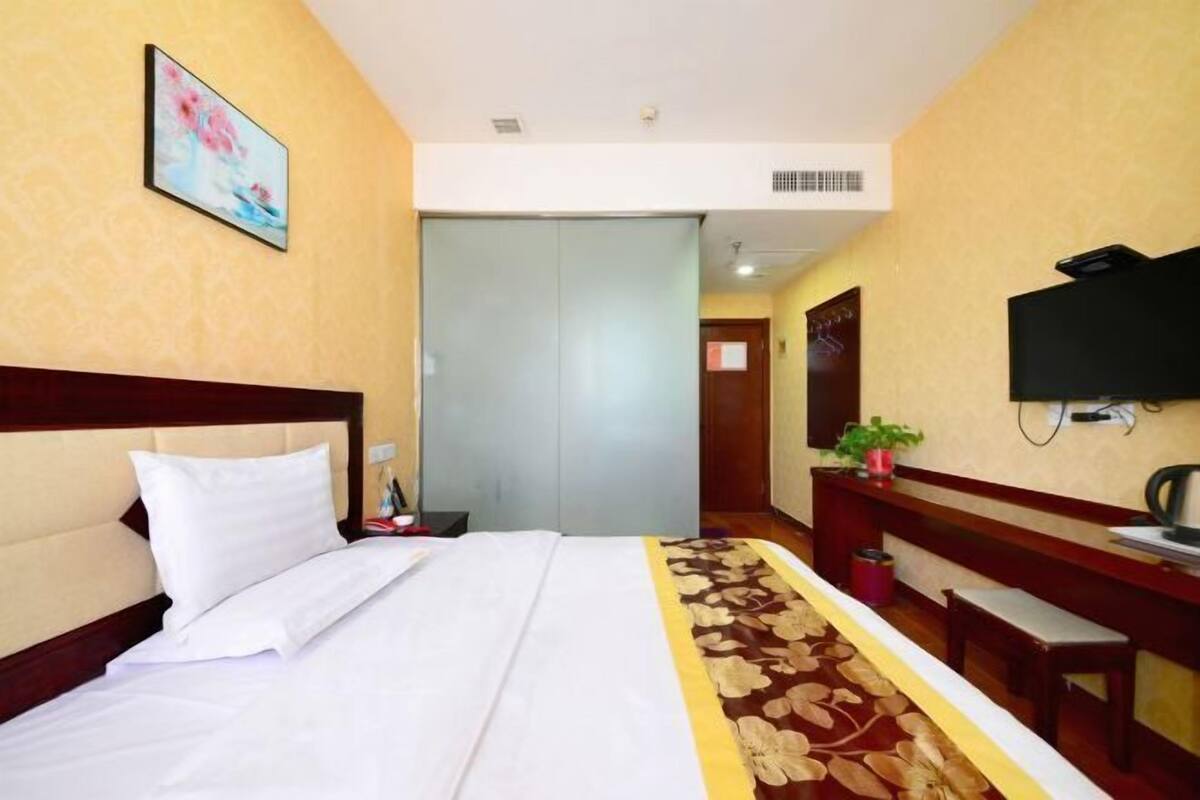 A hotel room with a bed, a desk, a television, and a wardrobe.