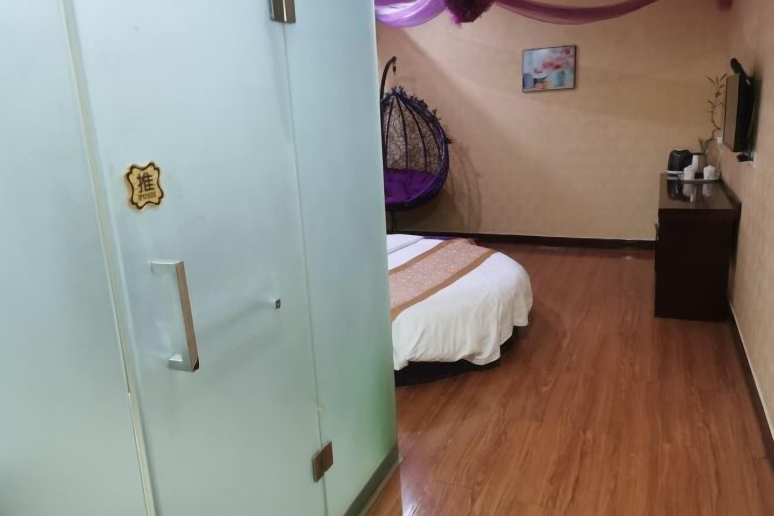 A room with a bed, a chair, a small table, and a wall-mounted TV.