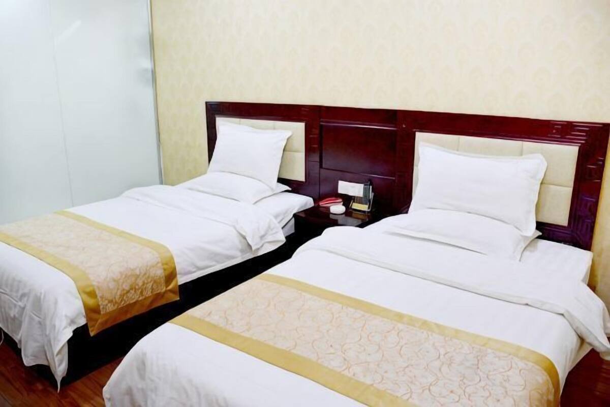 Two twin beds with wooden headboards, white linens, and a bedside table with a lamp.