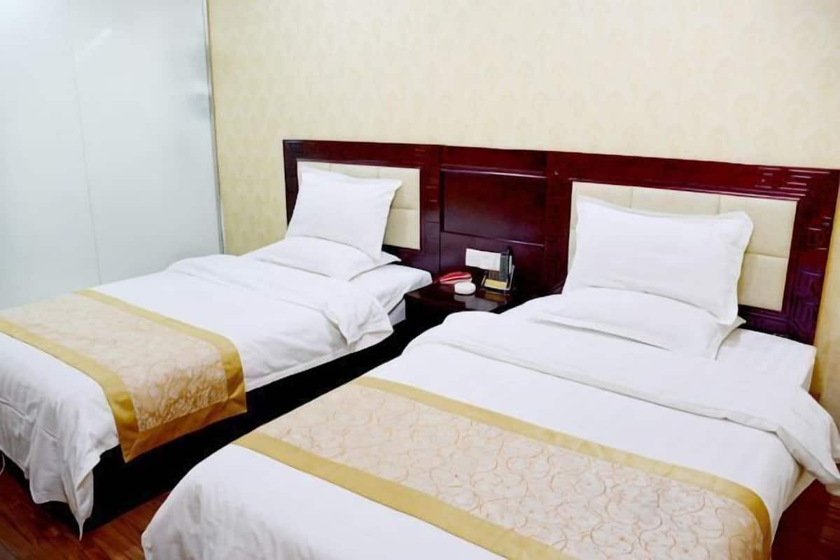 Two twin beds with wooden headboards, white linens, and a bedside table with a lamp.