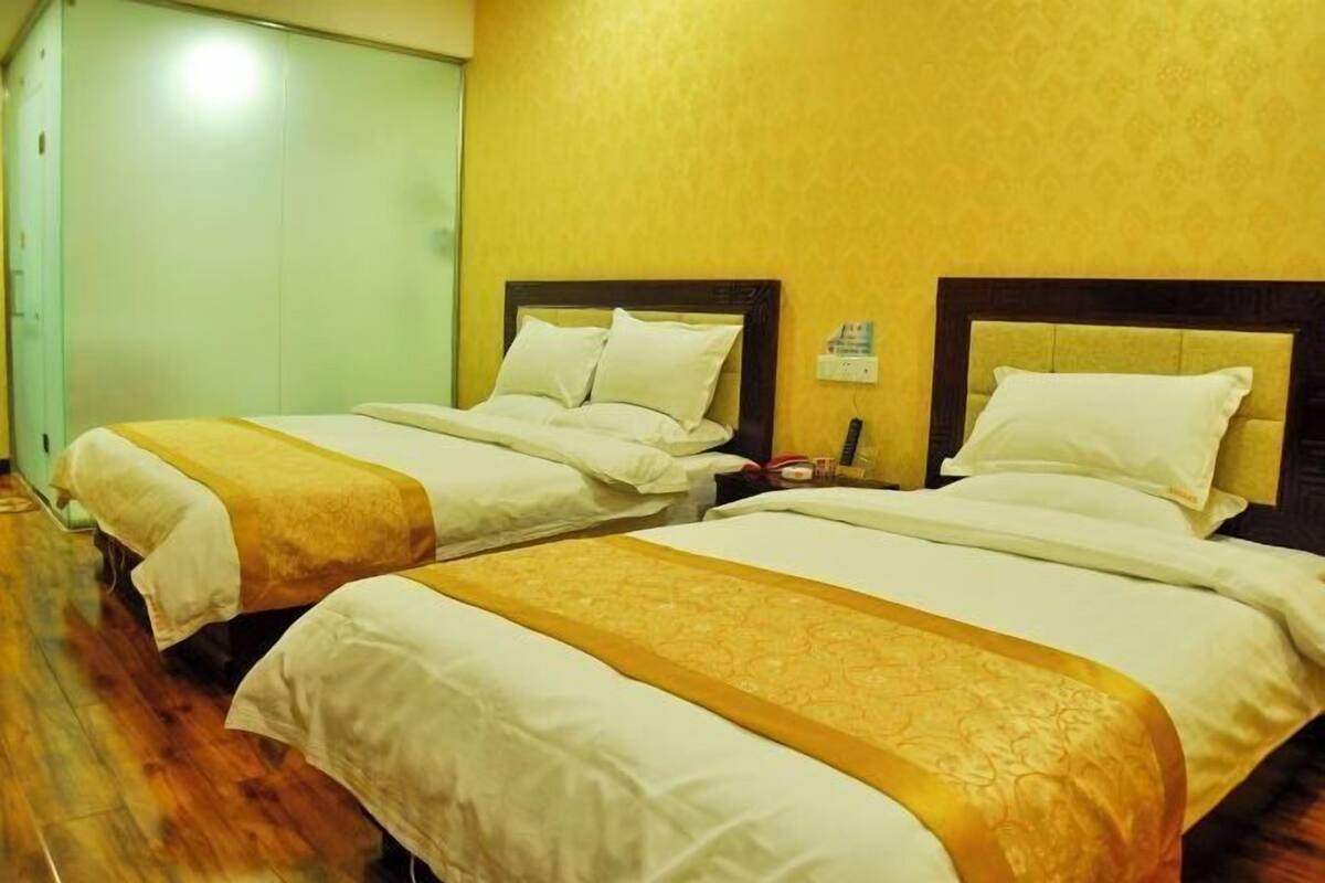 Two double beds with headboards, a wooden floor, and a yellow wall.
