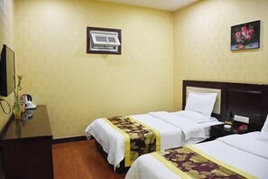 Habitación de hotel con dos camas, un escritorio, un televisor y aire acondicionado instalado en la pared.