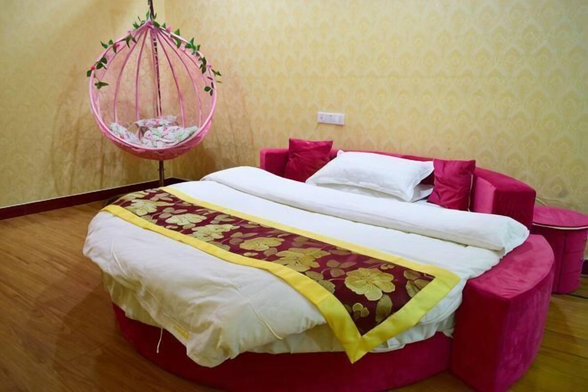 A room with a bed, a hanging chair, and a small table.