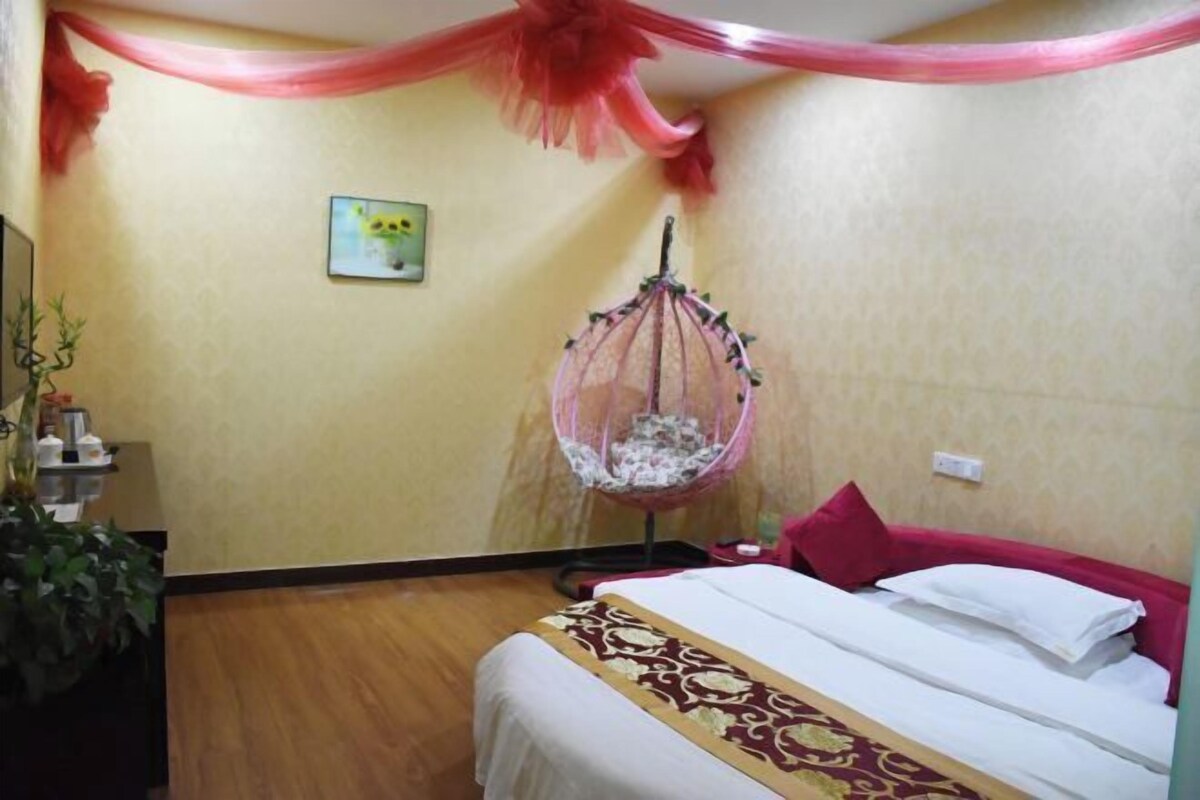 Una habitación de hotel con una cama, una silla colgante y una mesita con una planta.