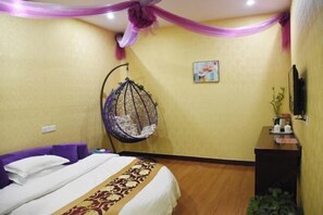 Habitación de hotel con cama, sillón colgante, escritorio y un cuadro en la pared.