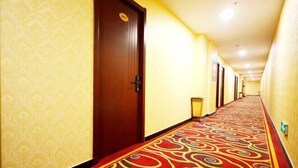 A hotel corridor with patterned carpet, wooden doors, and a yellow wall. - Taiyuan Baiyi Boutique Hotel (Taiyuan)