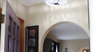 An interior hallway with wooden flooring, a chandelier, and a clock.
