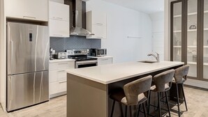 Een moderne keuken met roestvrijstalen apparatuur, een centraal kookeiland met barkrukken en een ingebouwde oven.