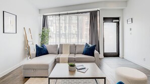 Een moderne woonkamer met een bank, salontafel en uitzicht op de stad door grote ramen.