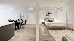 Een modern appartement met een eethoek, een groot bed en een klein nachtkastje.