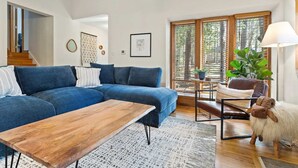 A modern living room with a blue sectional sofa, a wooden coffee table, a brown leather chair, and a decorative sheep statue.