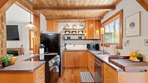 A modern kitchen with wooden cabinets, stainless steel appliances, and a large window providing natural light.