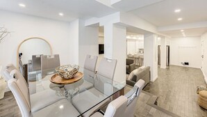 Un espace repas moderne avec une table en verre, des chaises blanches et un vase décoratif servant de centre de table.