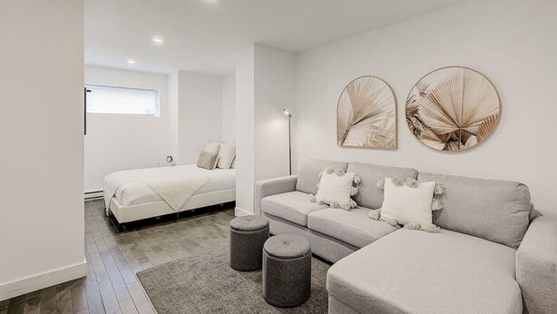 Une chambre à coucher moderne avec un lit, un canapé gris et deux œuvres d’art rondes accrochées au mur.
