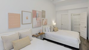 Une chambre d’hôtel avec un grand lit, un plus petit lit, une table de chevet et un mur orné de tableaux.