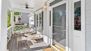A covered porch with white railings, a ceiling fan, and two wicker chairs. - Fenced In|Pets OK|By DT Apex|King Bed|EV Charger (Apex)