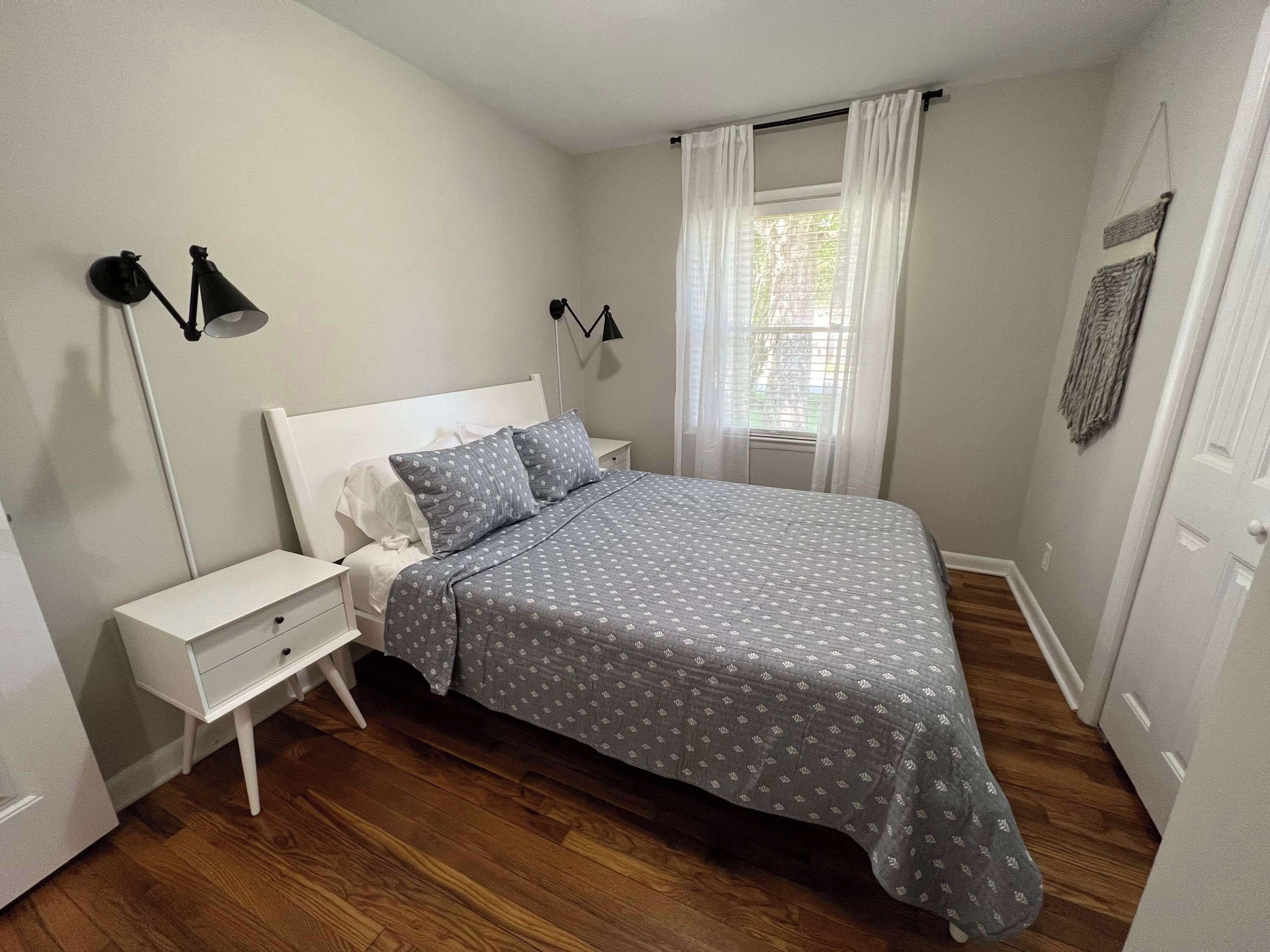 A bedroom with a bed, nightstands, a lamp, and a window with curtains.