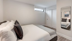 A bedroom with a bed, a mirror, and a window.