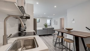 A modern kitchen with a stainless steel sink, a built-in stove, and a wooden dining table with bar stools.