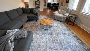 A living room with a sectional sofa, a round coffee table, and a grey armchair.
