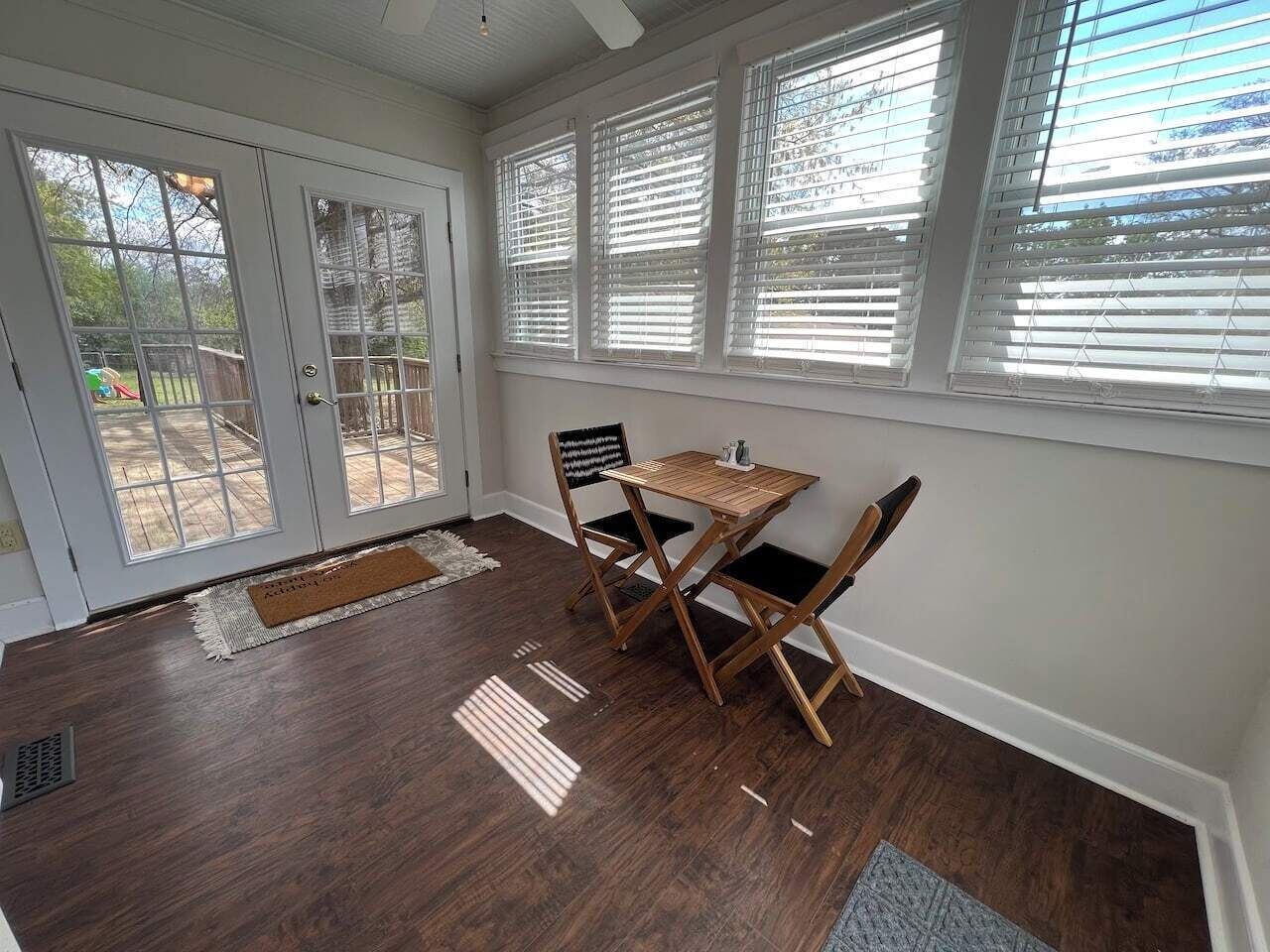 Een kamer met een eettafel en stoelen, een deur met glaspanelen en uitzicht op een achtertuin.