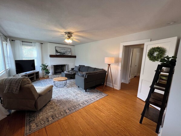 A living room with a fireplace, sofa, TV, and a floor lamp.