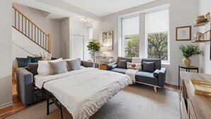 Een ruime slaapkamer met een groot bed, twee sofa's, een bureau en een trap.