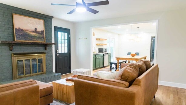 A living room with a fireplace, a ceiling fan, and a dining area with a table and chairs.