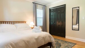 A neatly made bed with a wooden headboard, a bedside lamp, and a folded towel on the bed.