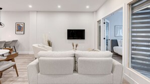 Un salon moderne comprenant un ensemble de canapés, une table à manger et un téléviseur fixé au mur.