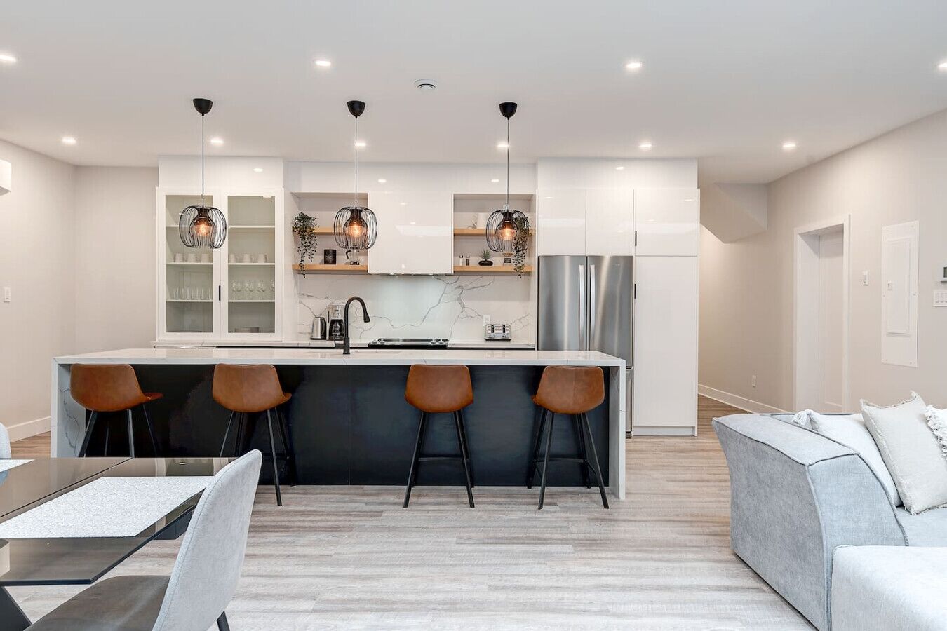 A modern kitchen with a central island, bar stools, and pendant lighting.