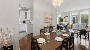 Un comedor con candelabro, paredes blancas y vistas al exterior.