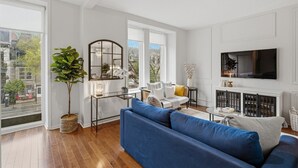 Una sala moderna con un sofá azul, una mesa de centro de vidrio y un espejo grande.