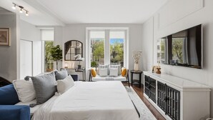 Un dormitorio con una cama grande, un escritorio, una silla, un televisor y vistas al exterior.