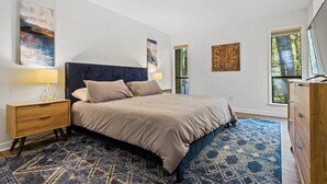 A bedroom with a bed, nightstands, a dresser, and artwork on the walls.