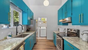 A kitchen with teal cabinets, a white stove, and a microwave.