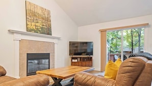 A living room with a fireplace, leather sofas, a wooden coffee table, and a TV.