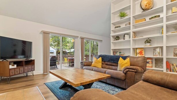 A modern living room with a sofa, coffee table, TV, and shelves.