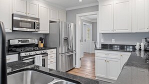 A modern kitchen with white cabinets, stainless steel appliances, and a granite countertop.