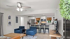 A modern living room with a ceiling fan, a dining area with chairs, and a kitchen with appliances. - Fenced In|Updated|Pets OK|3 Bed 2 Bath|Walkable DT (Zebulon)