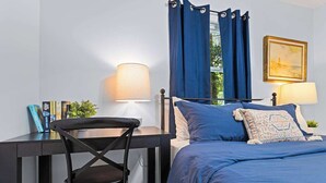 A bedroom with a bed, a desk with a chair, a lamp, and a painting on the wall. - Fenced In|Updated|Pets OK|3 Bed 2 Bath|Walkable DT (Zebulon)
