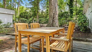 A wooden deck with a table and chairs, surrounded by trees and a white building. - Fenced In|Updated|Pets OK|3 Bed 2 Bath|Walkable DT (Zebulon)