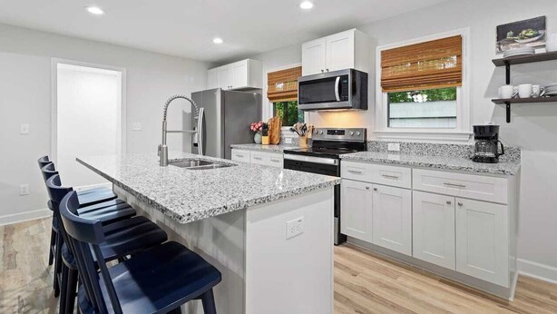 A modern kitchen with white cabinetry, a granite countertop, and stainless steel appliances. - Fenced In|Updated|Pets OK|3 Bed 2 Bath|Walkable DT (Zebulon)