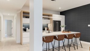Eine moderne Küche mit einer zentralen Kochinsel, Barhocker und einer dunklen Akzentwand.